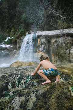 toddler siting in natural hot springs outdoors in winter