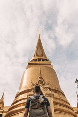 Fototapeta premium Vertical shot of a person standing in front of the Wat Phra Kaew under a cloudy sky in Thailand