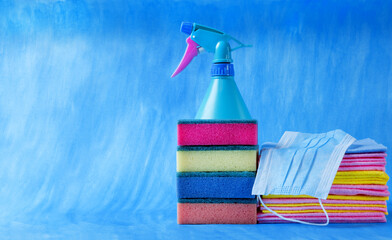 Multicolored cleaning supplies. Sponges, rags and spray against the blue background. Housekeeping...