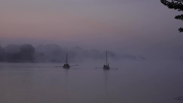 Two ancient authentic wooden boats on the water in the morning during a foggy dawn. Footage shot with natural light in 4K background with steady focus