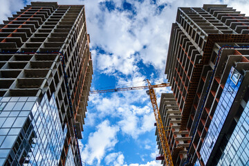 Two new high-rise buildings & working tower crane. Scenic cloudy sky is on background