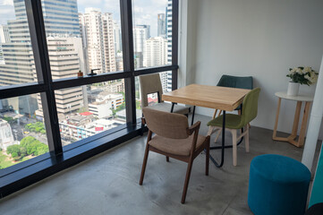 Wooden desk with chairs at side window of coworking space in downtown