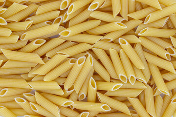 Penne flat lay. Pasta secco photo texture. Dry pasta penne scatter top view. Whole wheat food for garnish or vegetarian dish. Traditional italian cuisine. Penne package design template. Pasta texture