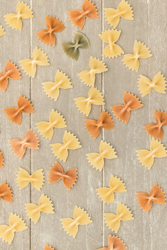 Pieces of pasta of various colors on a background wood, with natural light.