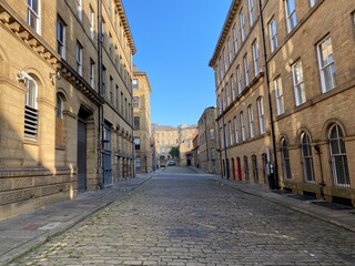 Looking along, Cater Street, at former textile buildings, built with Yorkshire stone in, Little Germany, Bradford, UK