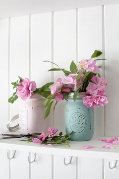 Painted jam jars with pink roses on shelf