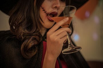 A teenage girl drinking cocktail at a halloween party