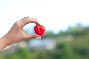 woman holding red heart in nature