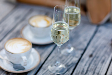 Closeup of two glasses of champagne and two cups of cappuccino or coffee for romantic breakfast in outdoor cafe or hotel restaurant