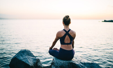 Slim female practicing meditation on seashore