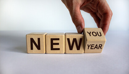 Hand turns a cube and changes the expression 'new year' to 'new you'. Beautiful white background. Copy space. Business concept.