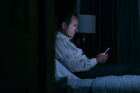 Business: Man Laying On Bed Using Cel Phone