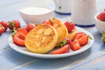 Sweet Cottage cheese pancakes on plate served strawberries. Russian syrniki, ricotta fritters or curd fritters.