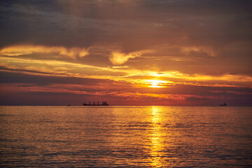 Fototapeta na wymiar Sunset on the sea, ships standing on the horizon.