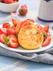 Sweet Cottage cheese pancakes on plate served strawberries. Russian syrniki, ricotta fritters or curd fritters.
