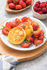 Sweet Cottage cheese pancakes on plate served strawberries. Russian syrniki, ricotta fritters or curd fritters.