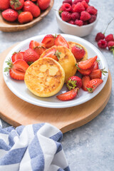 Sweet Cottage cheese pancakes on plate served strawberries. Russian syrniki, ricotta fritters or curd fritters.