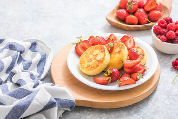 Sweet Cottage cheese pancakes on plate served strawberries. Russian syrniki, ricotta fritters or curd fritters.