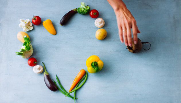 Hand arranging vegetables in heart shape