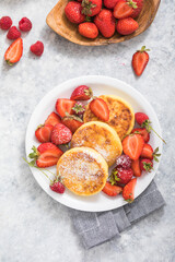 Sweet Cottage cheese pancakes on plate served strawberries. Russian syrniki, ricotta fritters or curd fritters.
