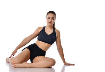 Fototapeta na wymiar Young sportswoman doing exercises sitting on a white background in the studio.