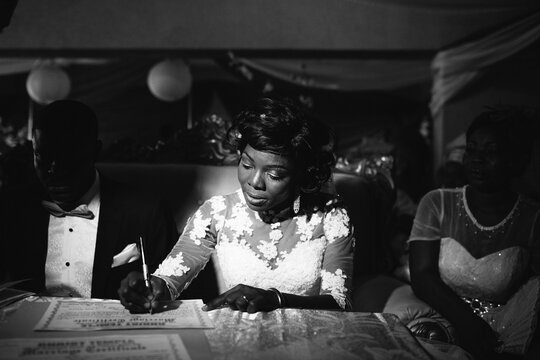 African woman signs the marriage register during her wedding ceremony.