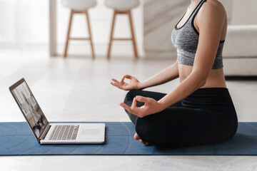 Close up fit woman coach has internet video online training of hatha yoga, practicing Sukhasana...