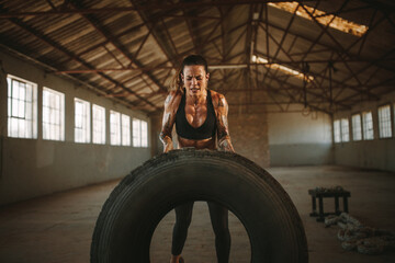 Muscular female working out with big tire