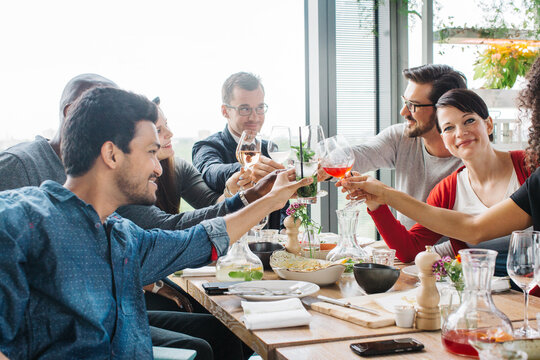 Group of Mixed Race Young People Clinking Glasses During Informal Restaurant Lunch