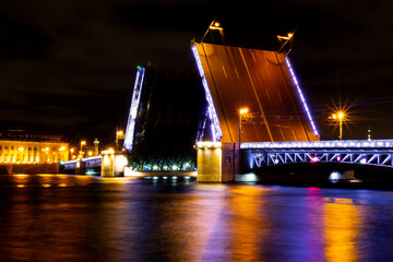 Fototapeta na wymiar Bright night landscape with raising of Palace drawbridge in Saint Petersburg, Russia. Opening the moveable bridge in the nighttime