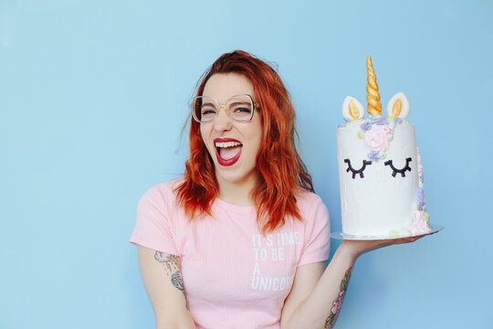 young redhead woman hanging a unicorn cake