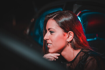 Fototapeta na wymiar chica joven de moda en un coche con luces de colores moderno