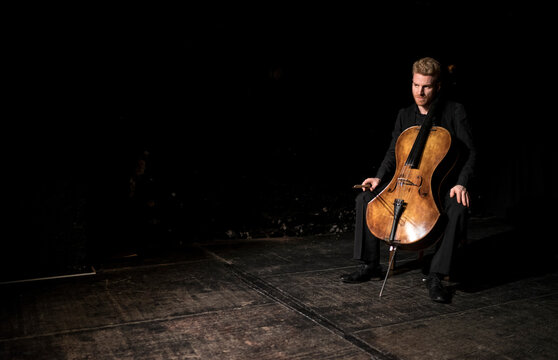 On-stage portrait of a cellist with his instrument