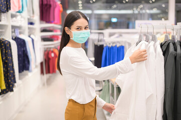 Woman wearing protective mask shopping under Covid-19 pandemic in shopping mall, social distancing...