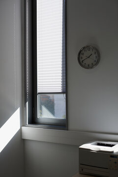 Wall clock and printer in a business office with a sunny window and nobody