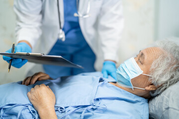 Doctor using stethoscope to checking Asian senior or elderly old lady woman patient wearing a face mask in hospital for protect infection Covid-19 Coronavirus.