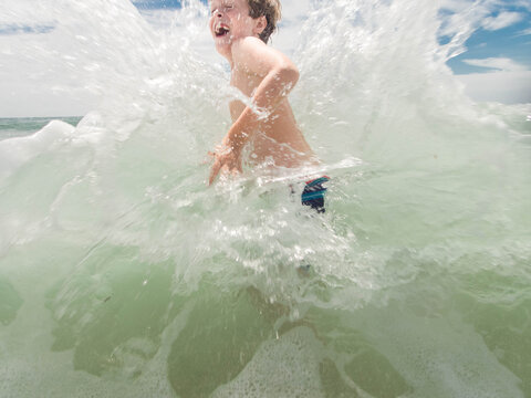Young Boy Splashing in Ocean Waves