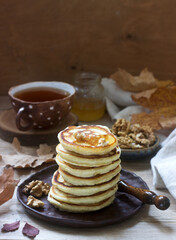 Vegetarian breakfast of fritters with honey, nuts and tea. Autumn still life.