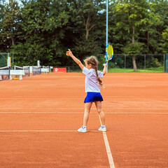 A kid with a tennis racket on the tennis court.