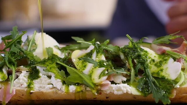 preparing food in home kitchen. cooking Breakfast or lunch in restaurant. Fast food close-up. male chef pours olive oil over large sandwich with cheese cucumber ham and salad. concept of healthy food