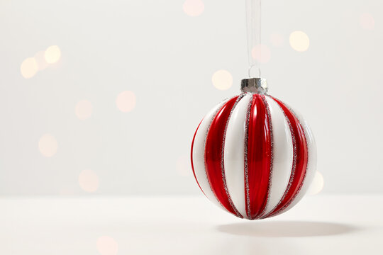 Creative, Christmas and new year, festive composition. a striped red-and-white glass balloon hangs on a light background. copy space. selective focus