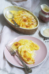 French dish Gratin Dauphinois in ceramic form on a light background. Rustic style.