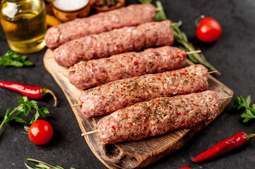 raw Lula kebab  on skewers with spices on a stone background 