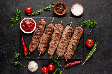 grilled Lula kebab on skewers with spices on a stone background

