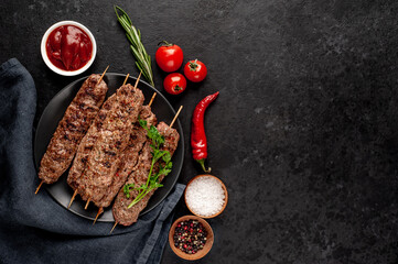 Grilled Lula kebab on skewers with spices in a black plate on a stone background with copy space