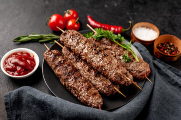 Grilled Lula kebab on skewers with spices in a black plate on a stone background