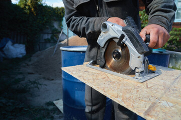 Close up electric saw to sawing wood board, solf focus. Plywood Cut by Circular Saw. Construction Worker and the Woodworking