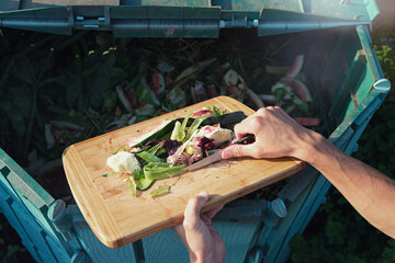 Person throws organic waste from his kitchen into compost heap. Composting - eco-friendly recycling...