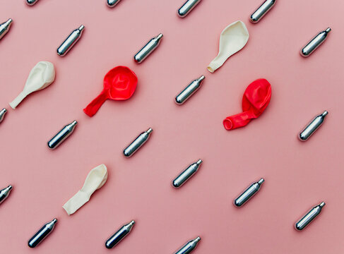 HIppy crack nitrous oxide canisters in a row over pink background