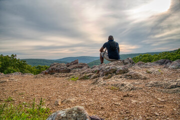 African American man sitting at the the top of a mountain enjoying the view during a hike.